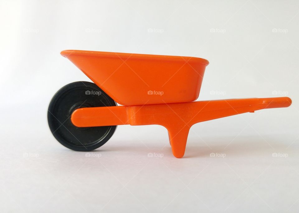 Plastic toy wheelbarrow against white background