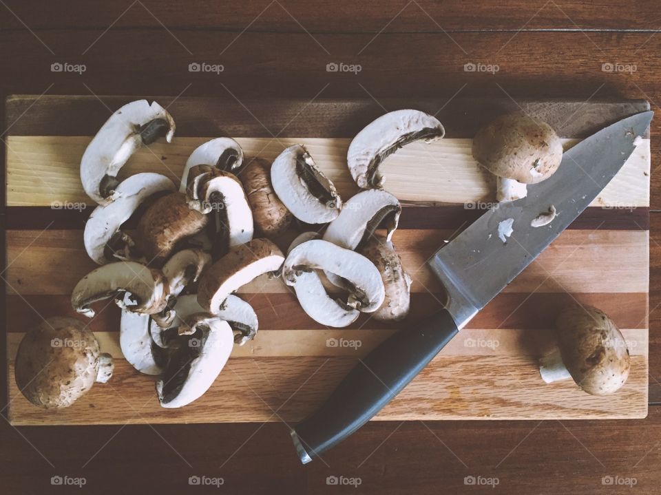 Mushrooms Au Natural. Fresh sliced baby Bella mushrooms with chefs knife on wooden cutting board