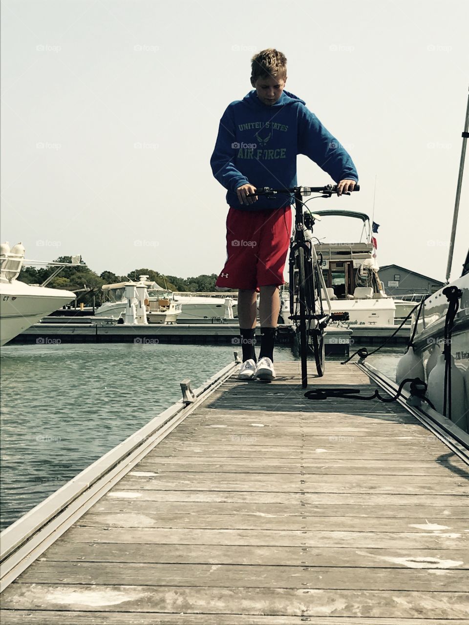 Boy walking with bicycle on pier