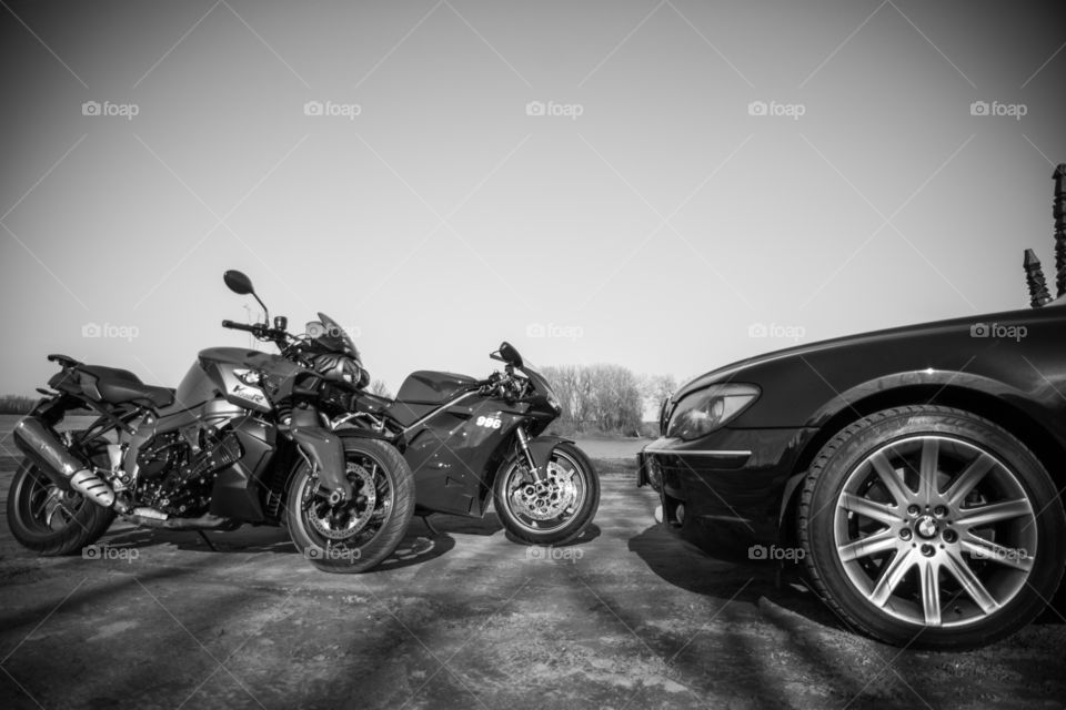 Sport motorcycles and bmw 7 besides river dock. Black and white photo