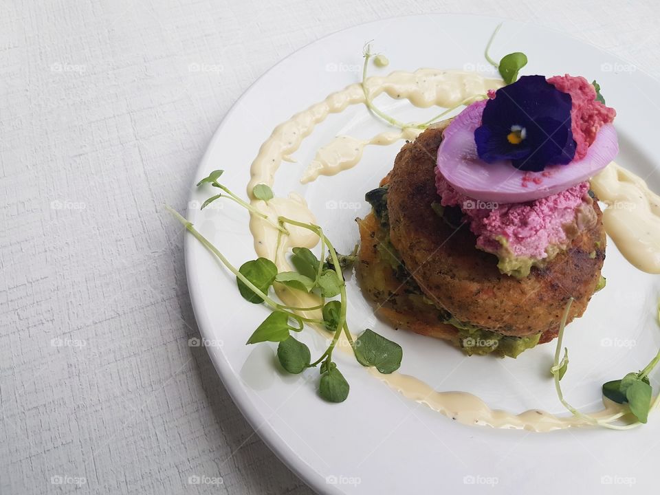 close up of beautiful plated resturant food salmon hash stack with microgreens and sauces