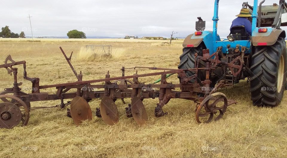 blue landini tractor pulling vintage disc plough