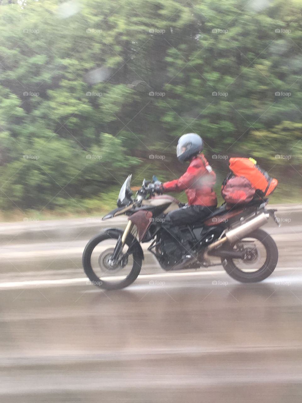 Rider on highway driving motorcycle in the cold & rain. Looks like he's packed and traveling.