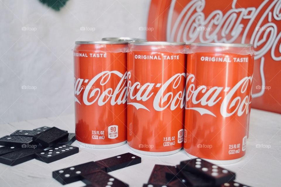 A six pack of Coca-Cola cans with dominos 