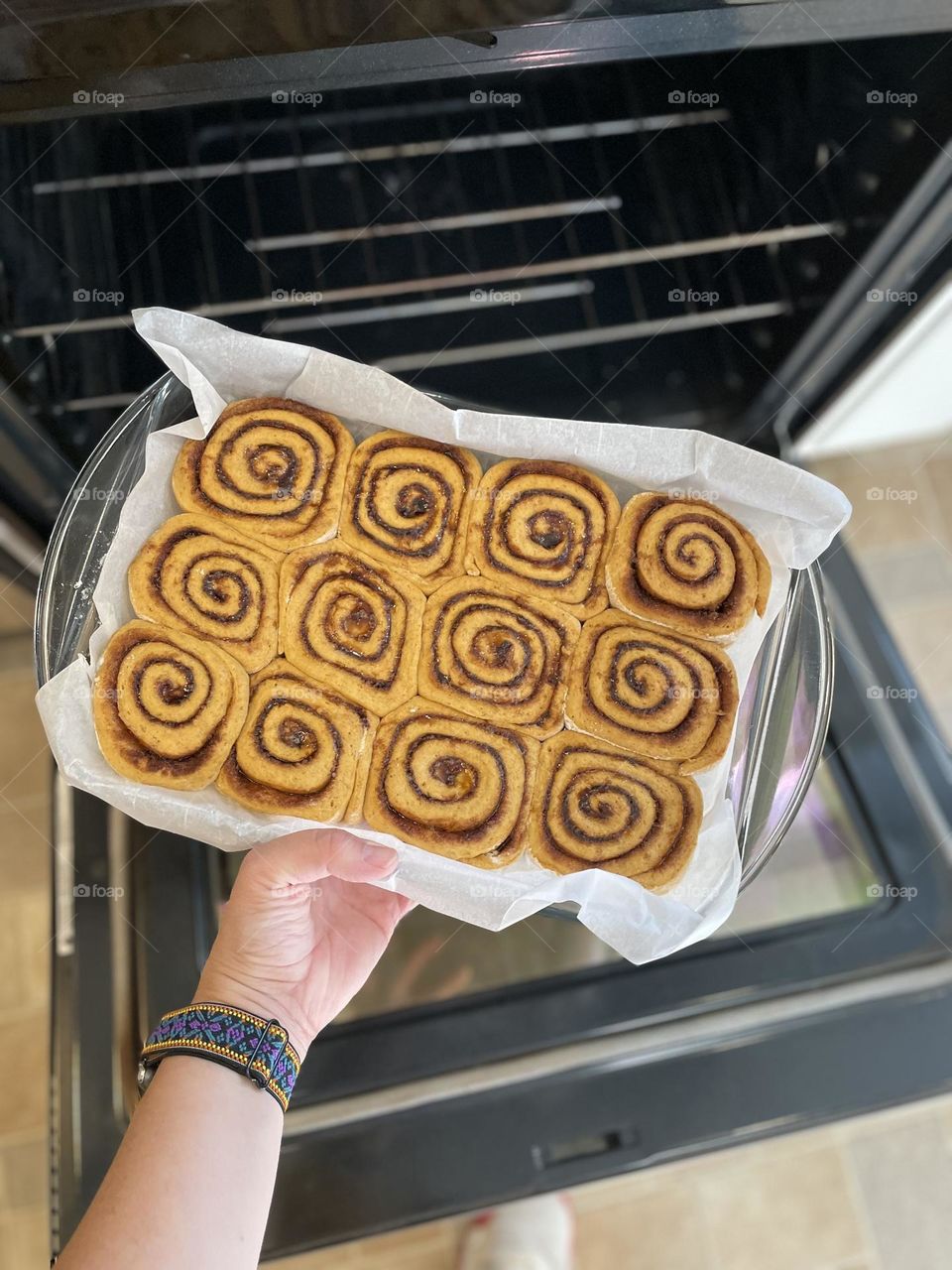 Woman puts freshly made cinnamon rolls into the oven, baking cinnamon rolls at home, making pumpkin cinnamon rolls with cream cheese