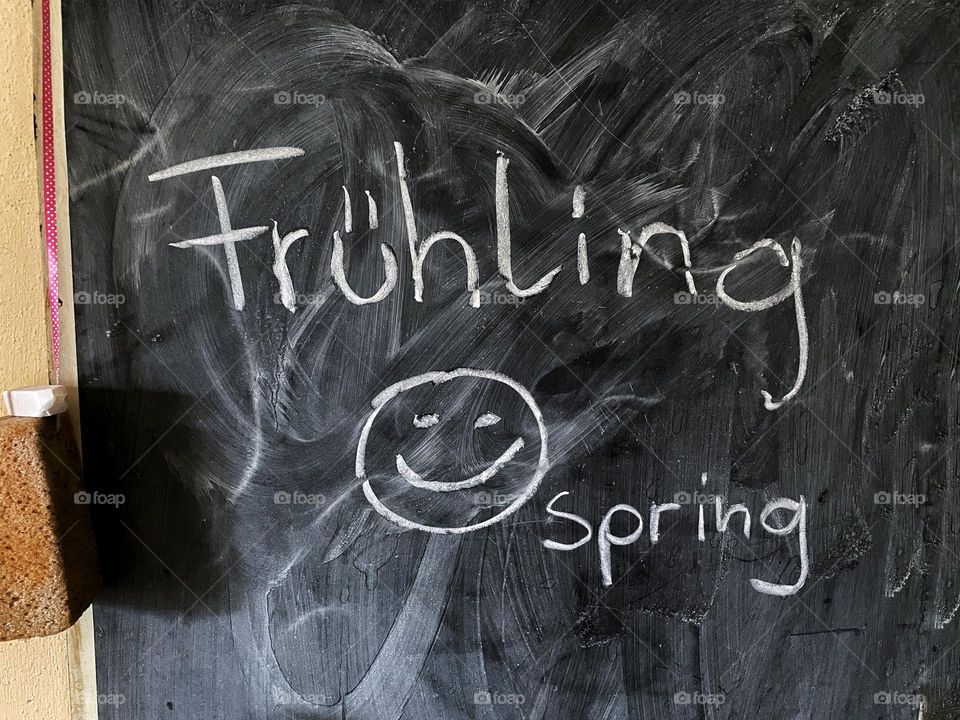 The word spring and Frühling written with white chalk on black chalkboard
