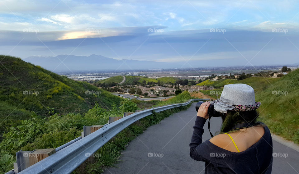 lady holding dslr camera, taking a photo of the hills in spring