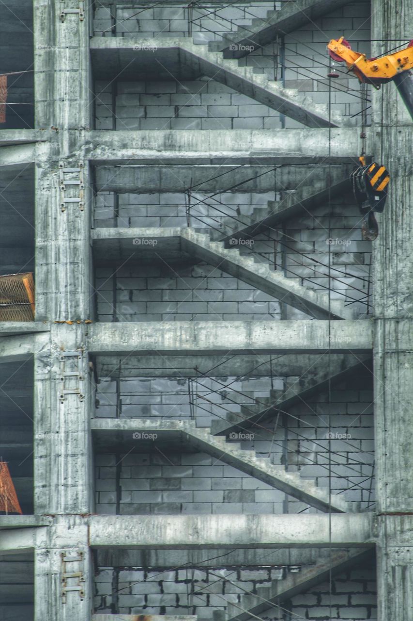 concrete structure of a multi-storey building under construction. flights of stairs are visible through the wall.