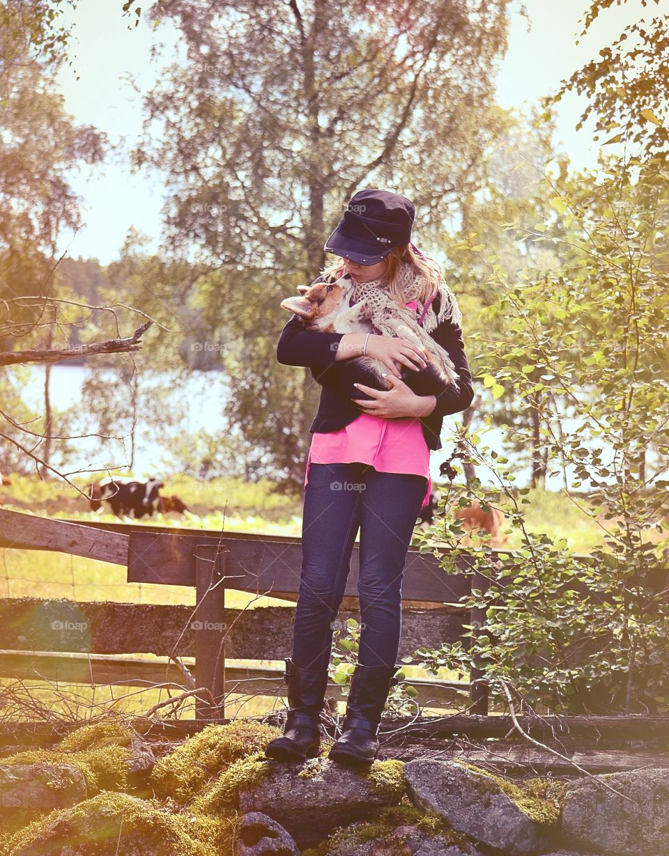 Cute. Girl holding her puppy with cows in the background