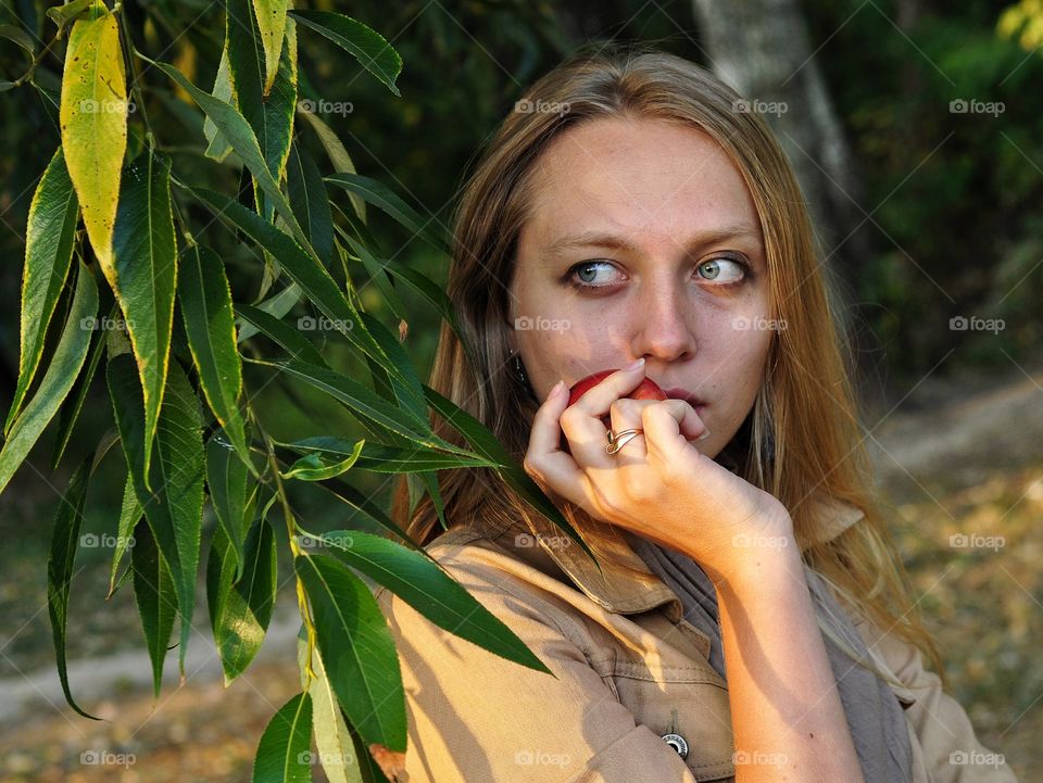 young pretty blonde woman with apple in the park