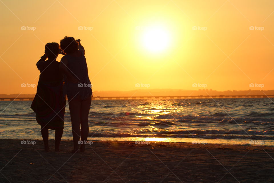 Mother and Daughter watching the Sunset on the beach 