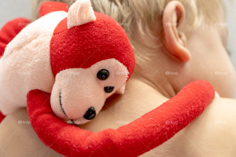 Red plush monkey hugs a sleeping boy