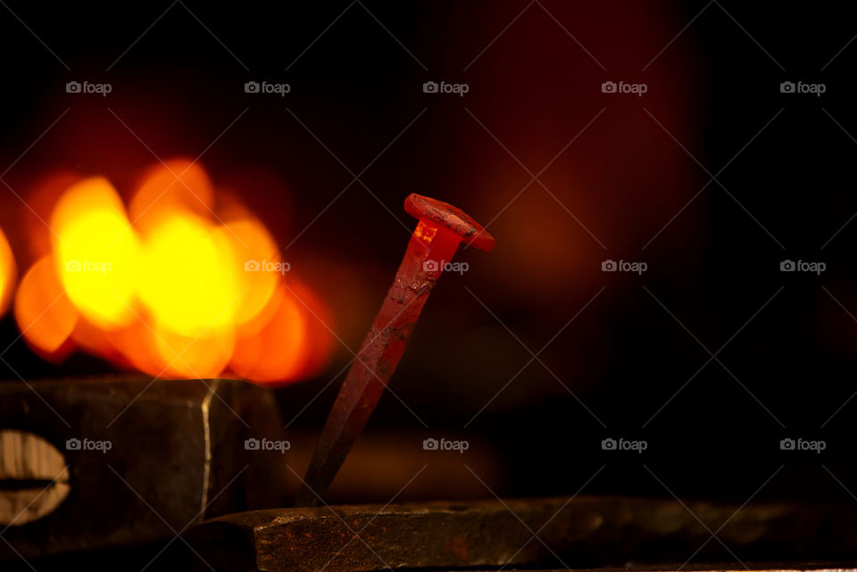 Closeup of hot metal nail on anvil in blacksmith workshop