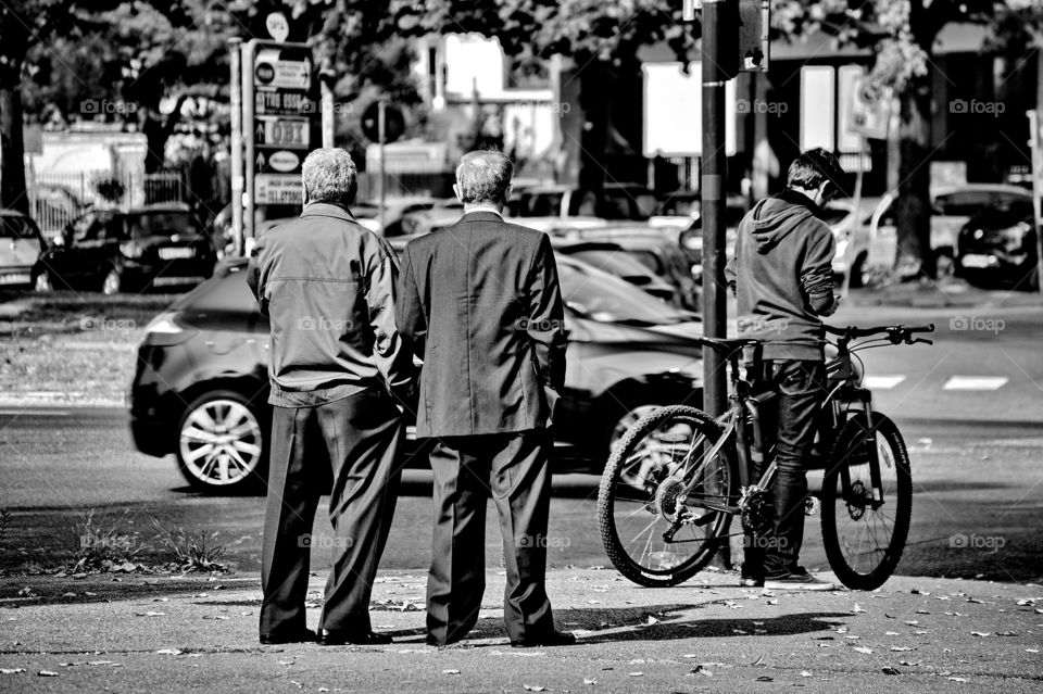 a pair of old men talk standing on the sidewalk