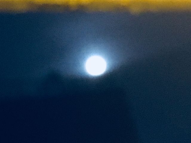 Another unusual photograph from 2018 of the full moon in the night sky over Long Island City, Queens, NY. The moon appears as if resting in a “cradle” made up of mist and clouds. Hypnotic Productions