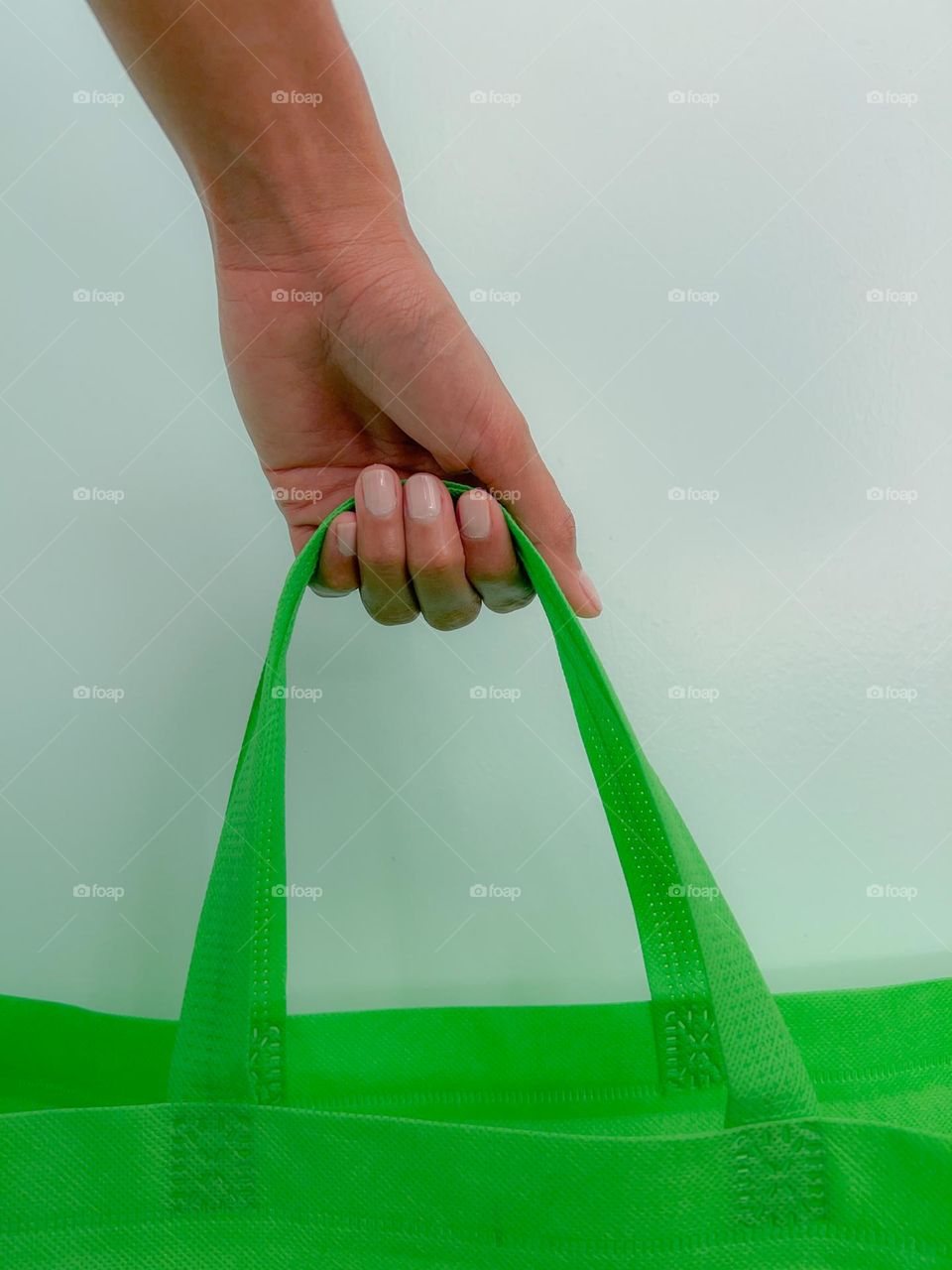 A person carrying a green bag with painted nails