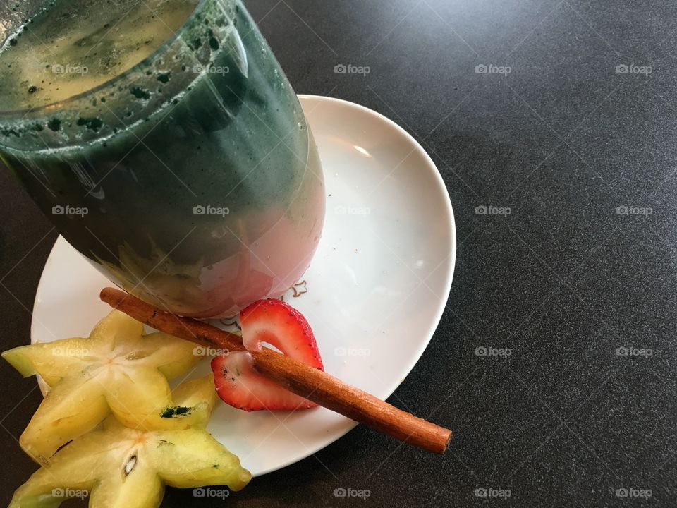 Delicious fresh fruit and protein smoothies with rainbow layers decorated with star fruit cinnamon and strawberry on plate ready to drink 