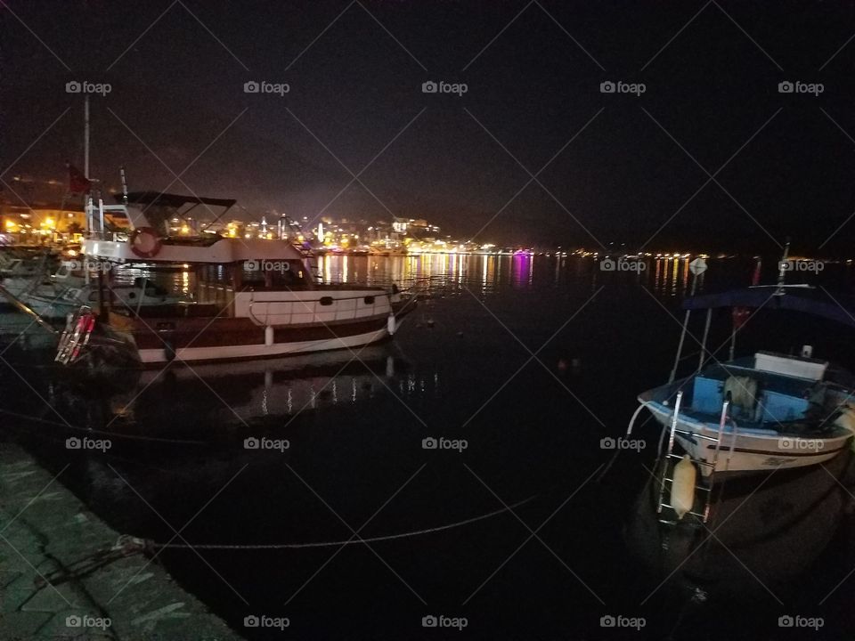 boats docked along the harbor in fethiye turkey with the city lights in the background