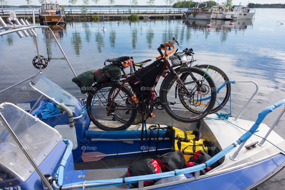 Taipalsaari, Finland – July 2, 2015: Two touring bikes tied securely to a fishing boat with colorful panniers on the boat floor by the lake Saimaa, Finland for crossing to the other side of the lake from Taipalsaari on 2 July 2015.