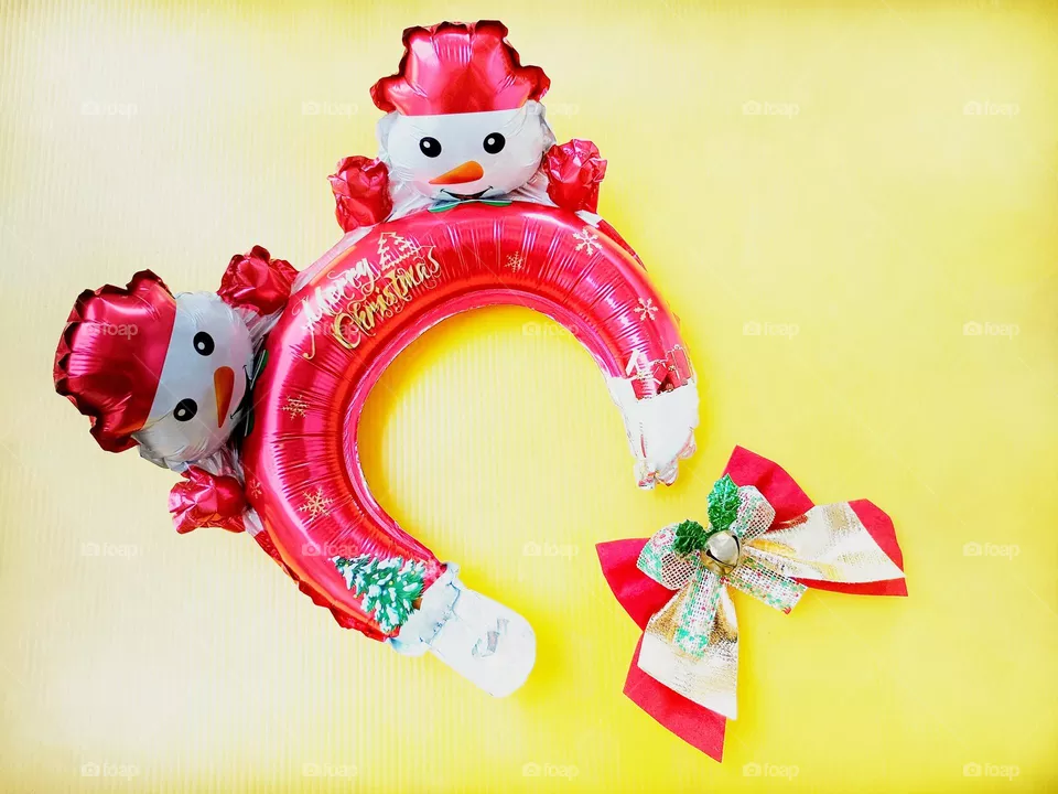 Snowman Christmas headband and Christmas bow on yellow background horizontal composition.