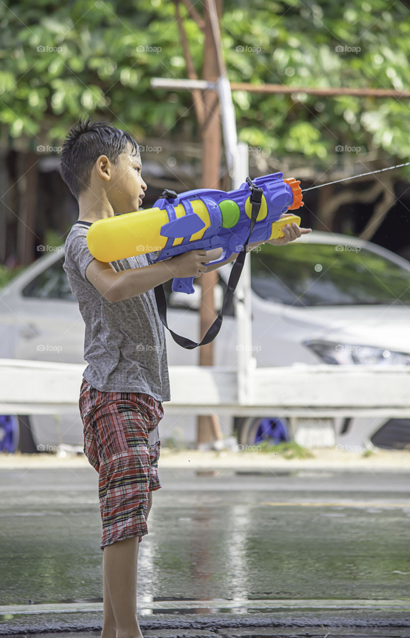 Asian boy holding a water gun play Songkran festival or Thai new year in Thailand.