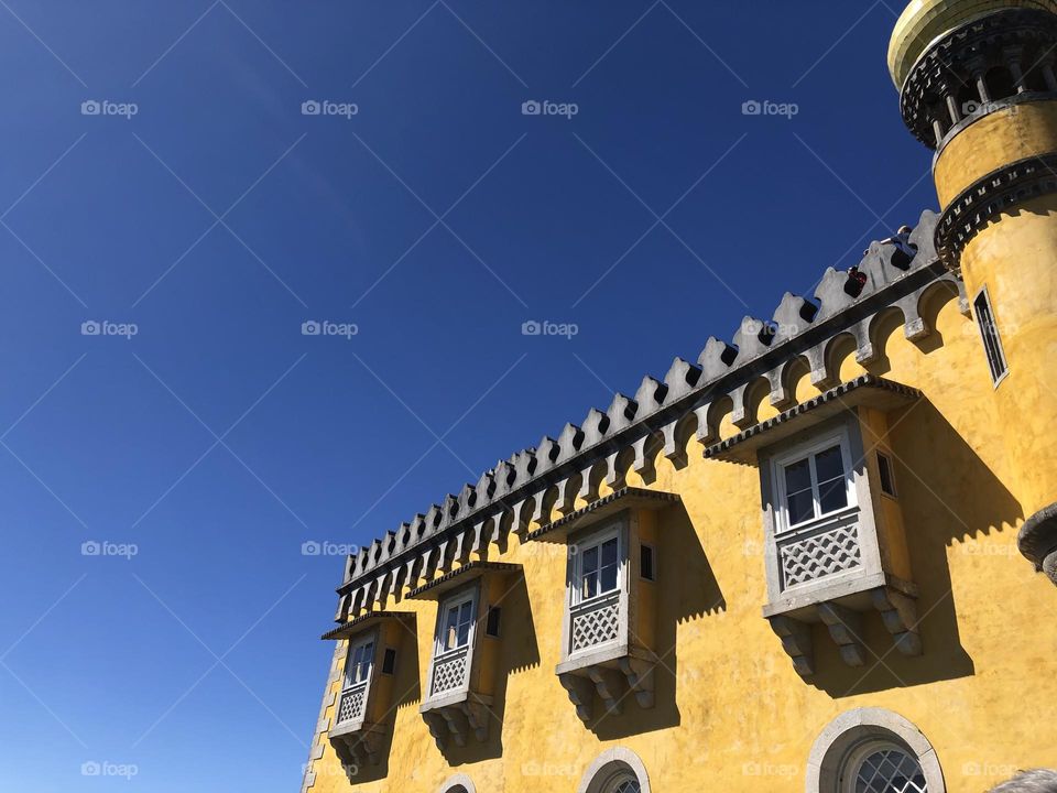 Facade of the Pena Palace in yellow color and a bright blue sky 