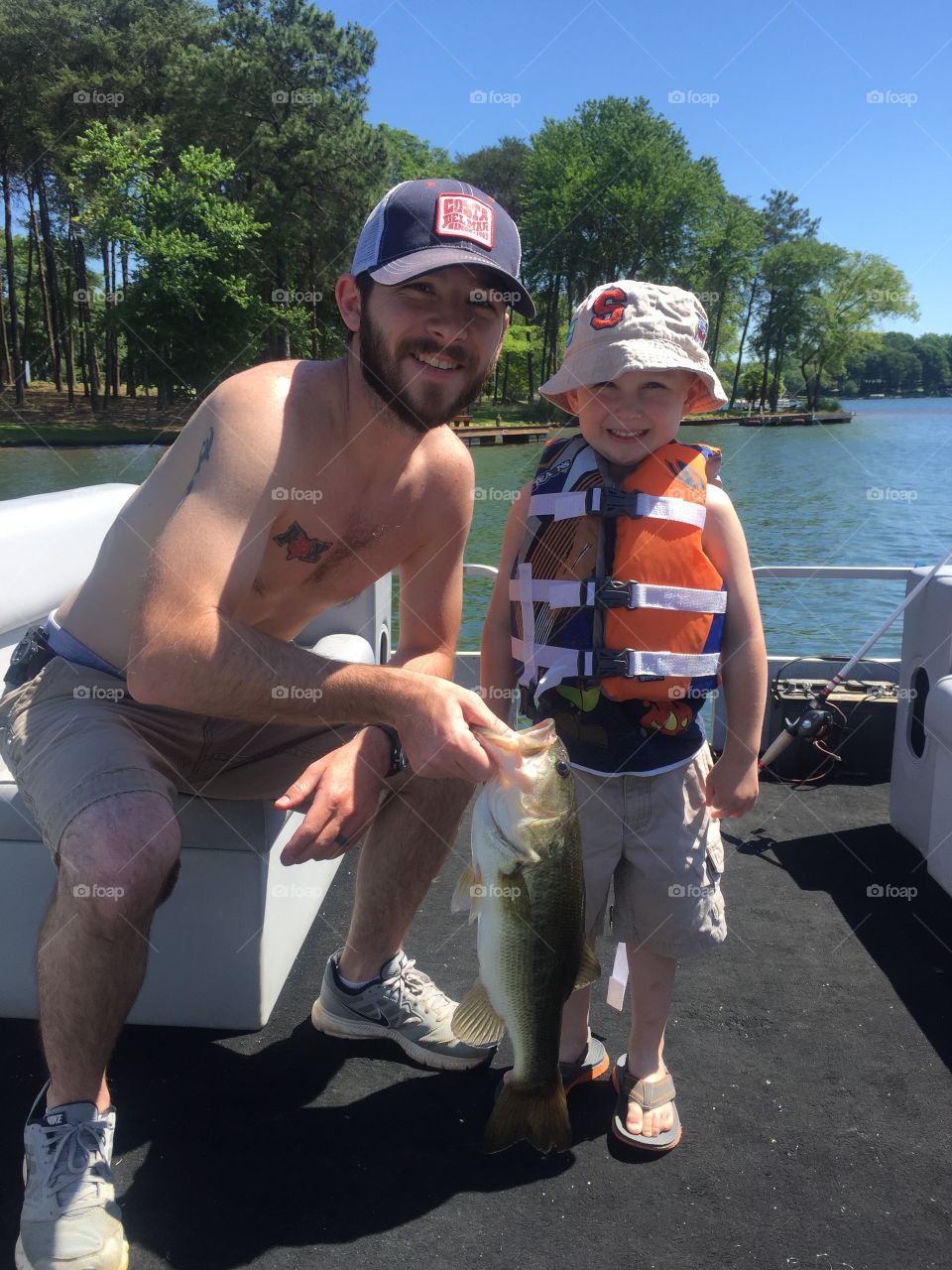 Portrait of happy father and son in ship holding dead fish in hand