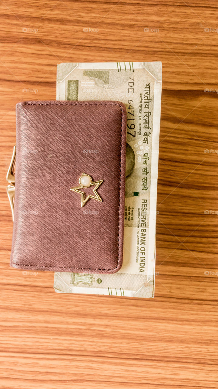 Indian five hundred (500) rupee cash note in brown color wallet leather purse on a wooden table. Business finance economy concept. High angel view with copy space room for text on right side of image.