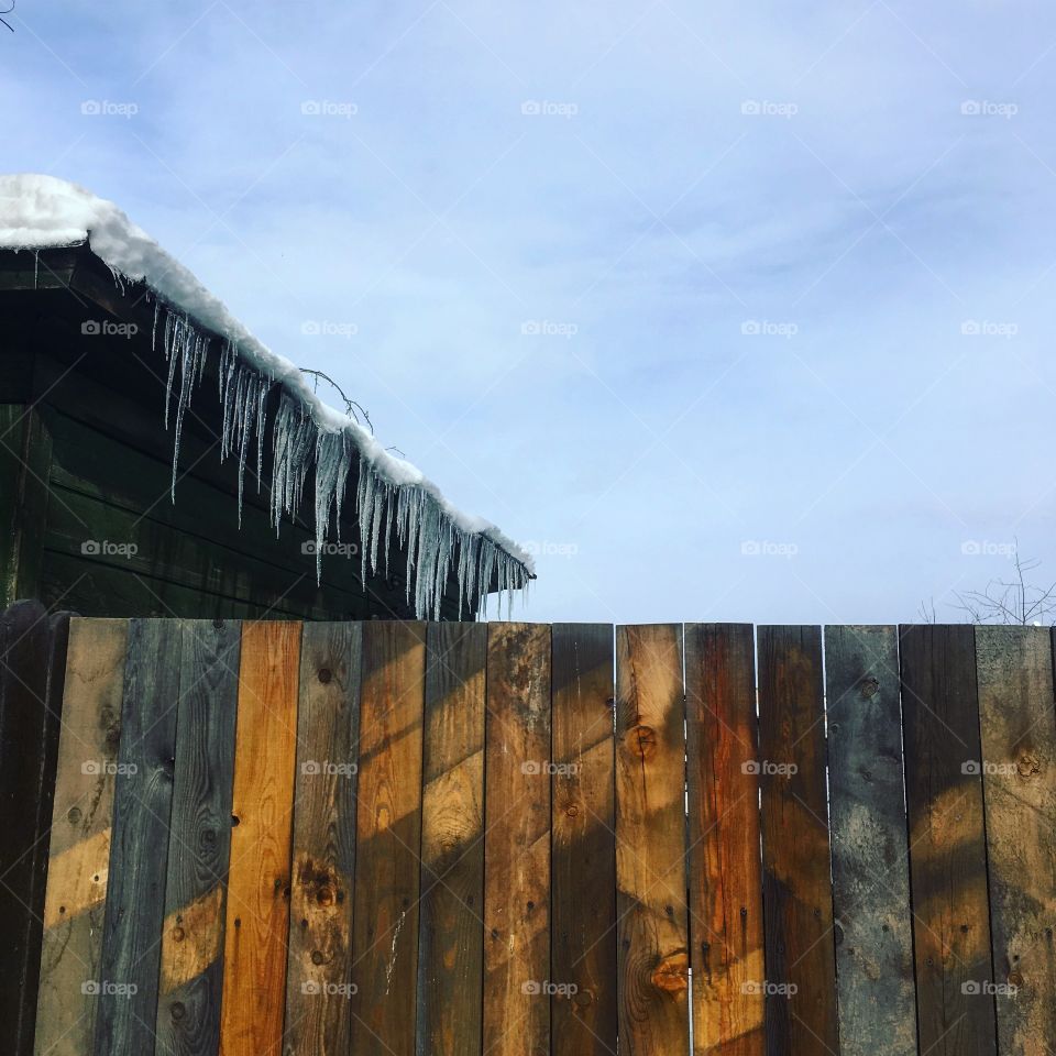 Wooden fence and icicles on the roof. 