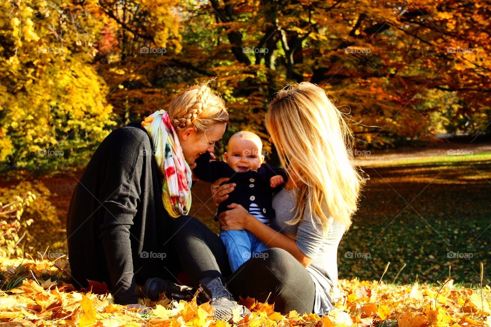 Mother and sister sitting in park with baby boy