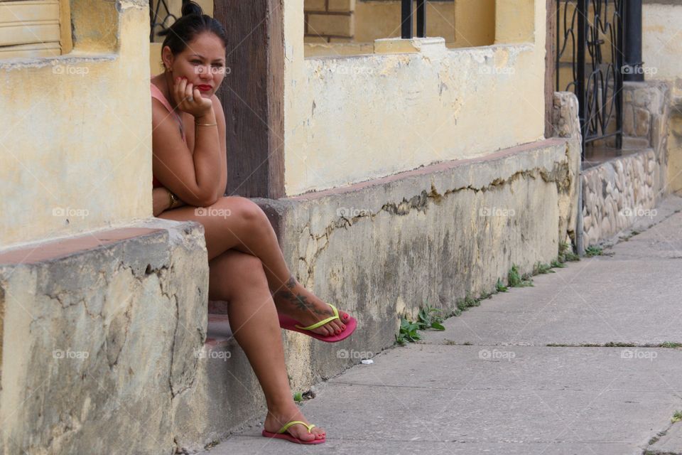 Cuban People.Thinking young woman sitting on front porch.