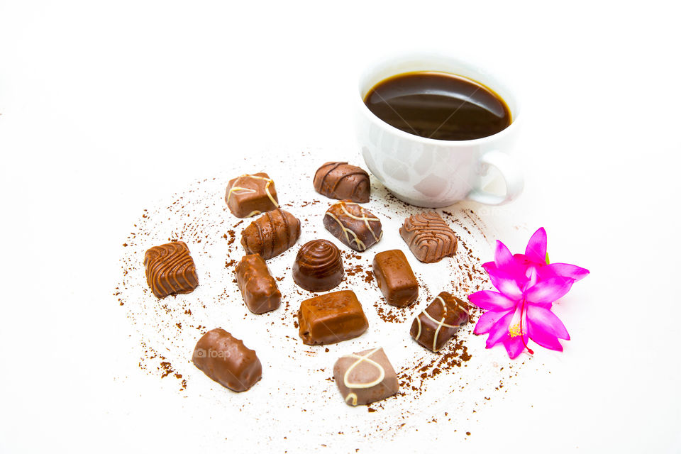 Delicious milk chocolate with coffee on a white background and pink flower. Many sweet delicious sugar chocolate