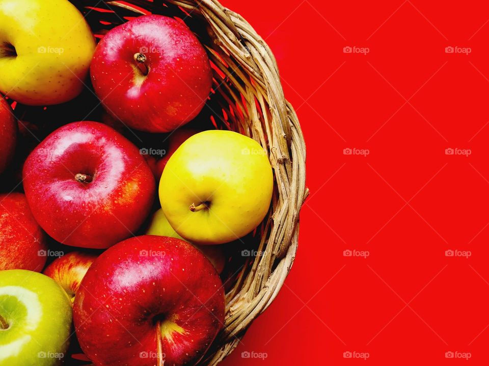 basket of apples on a red background photographed from above