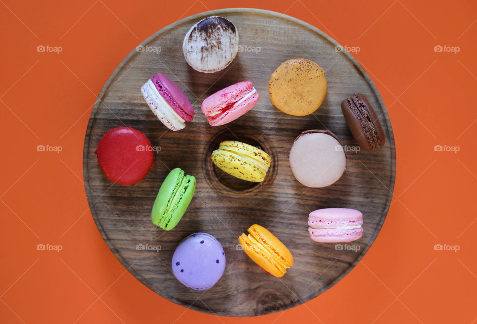 Macaroons on wooden plate, flat lay