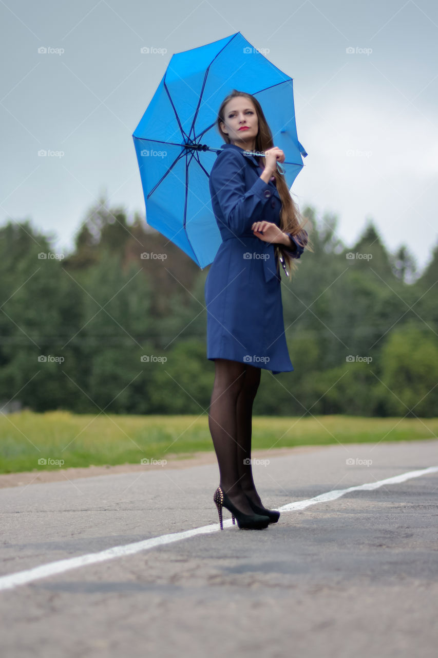 A beautiful long haired girl in a blue costume with the blue umbrella