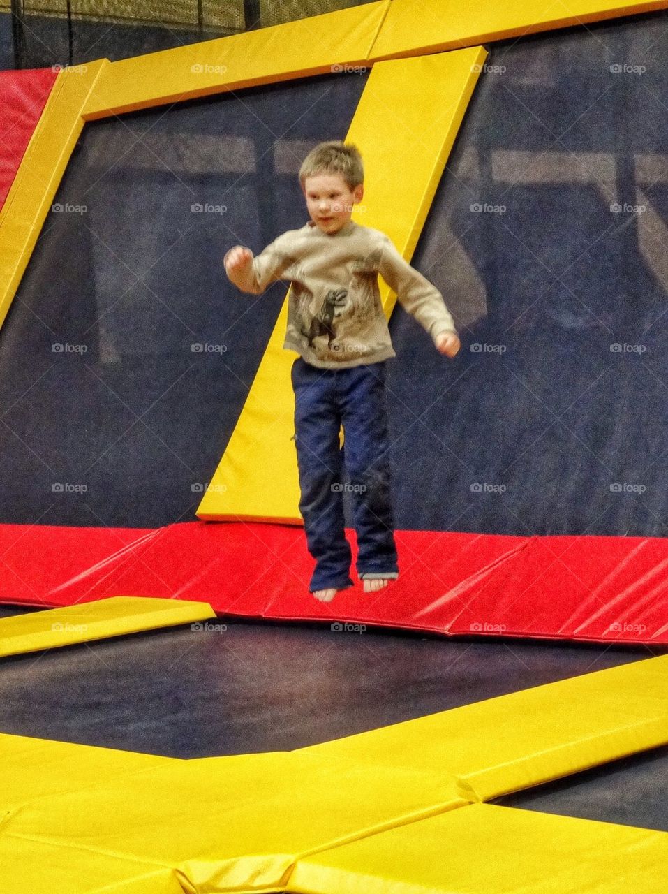 Jumping On A Trampoline. Boy Exercising On A Giant Trampoline
