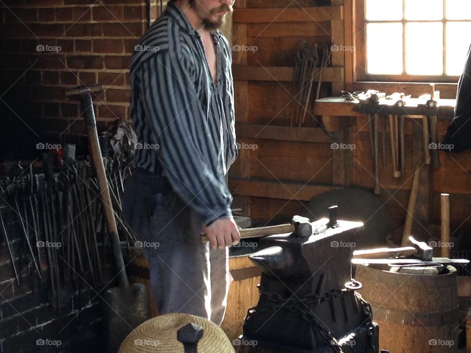 This blacksmith is dressed as if he lives in colonial times.