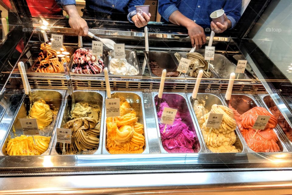 Many kinds of fruits icecreams in the department store, they are colorful, beautiful and look like delicious. have many persons' hands.This is interesting.