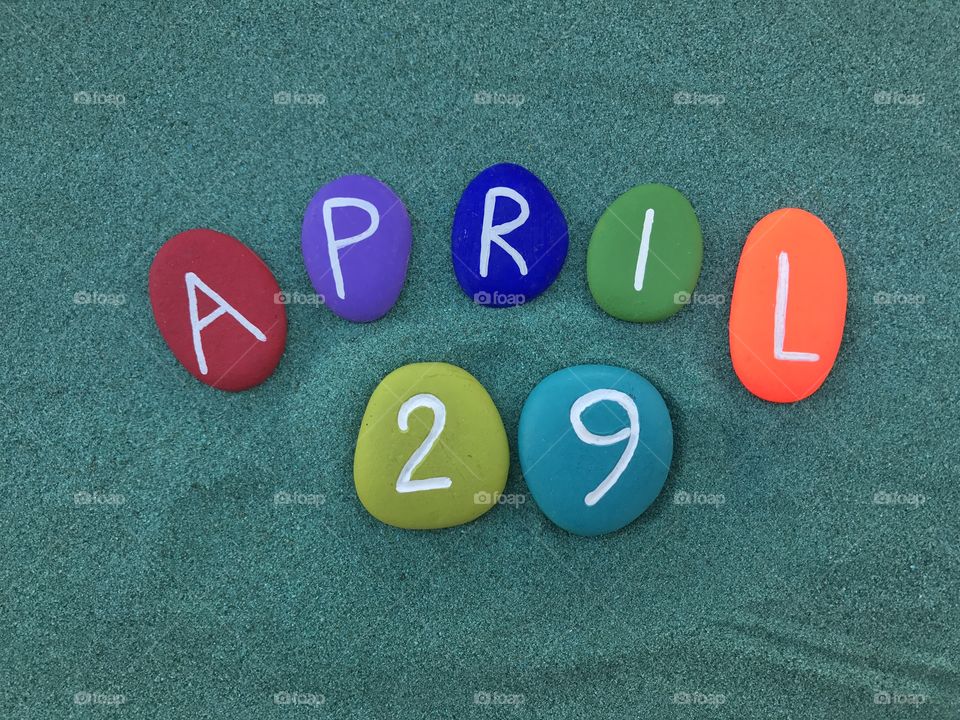 29 April, calendar date with colored stones over green sand 