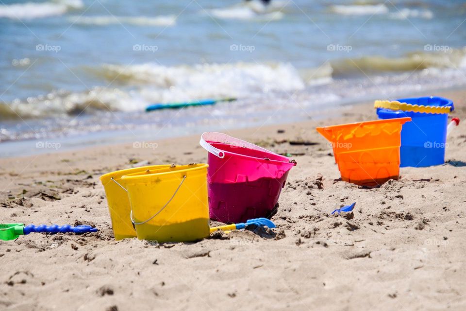 Colorful plastic buckets on a sandy beach