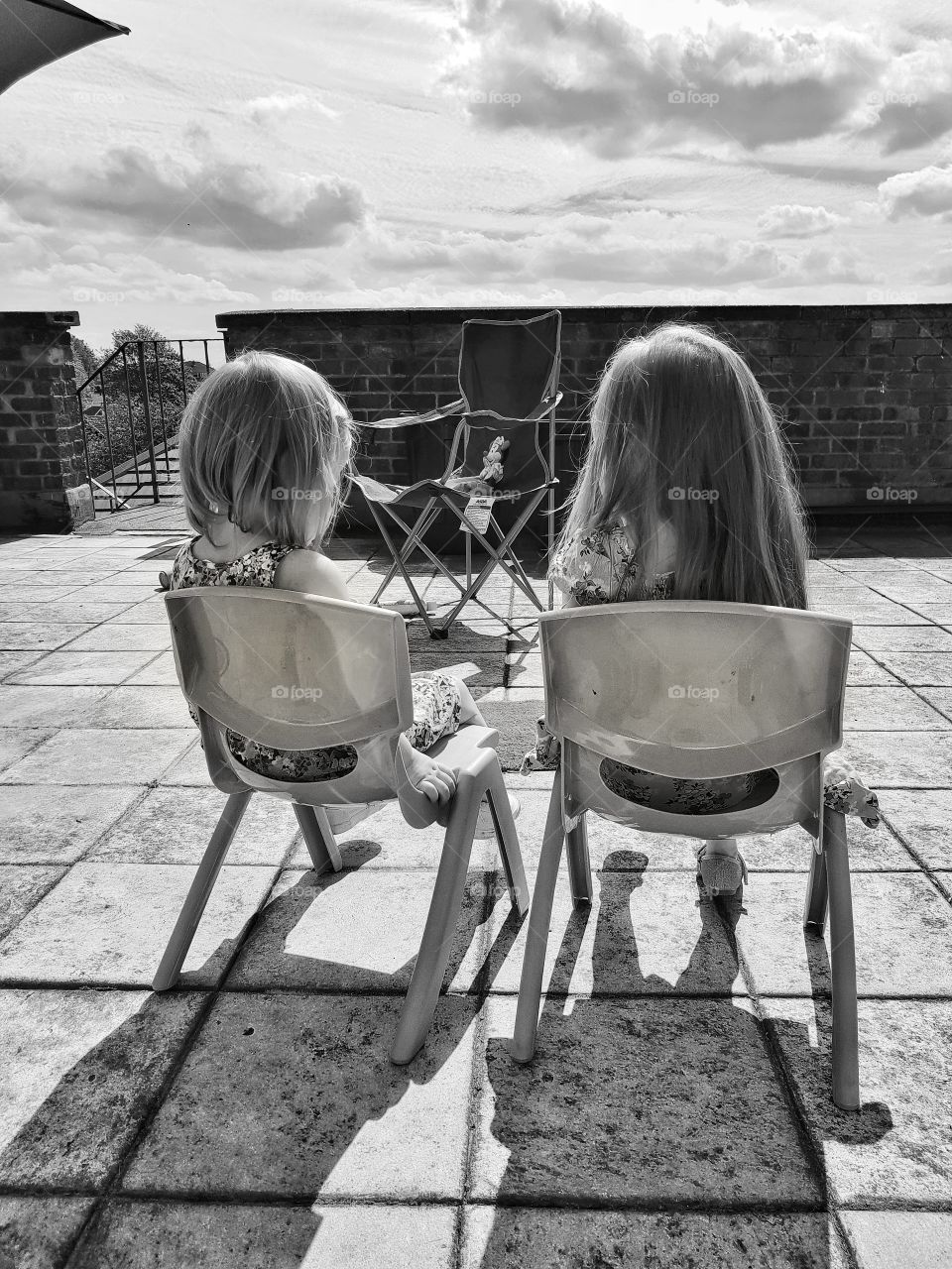 girls friends sisters sitting on chairs together on patio