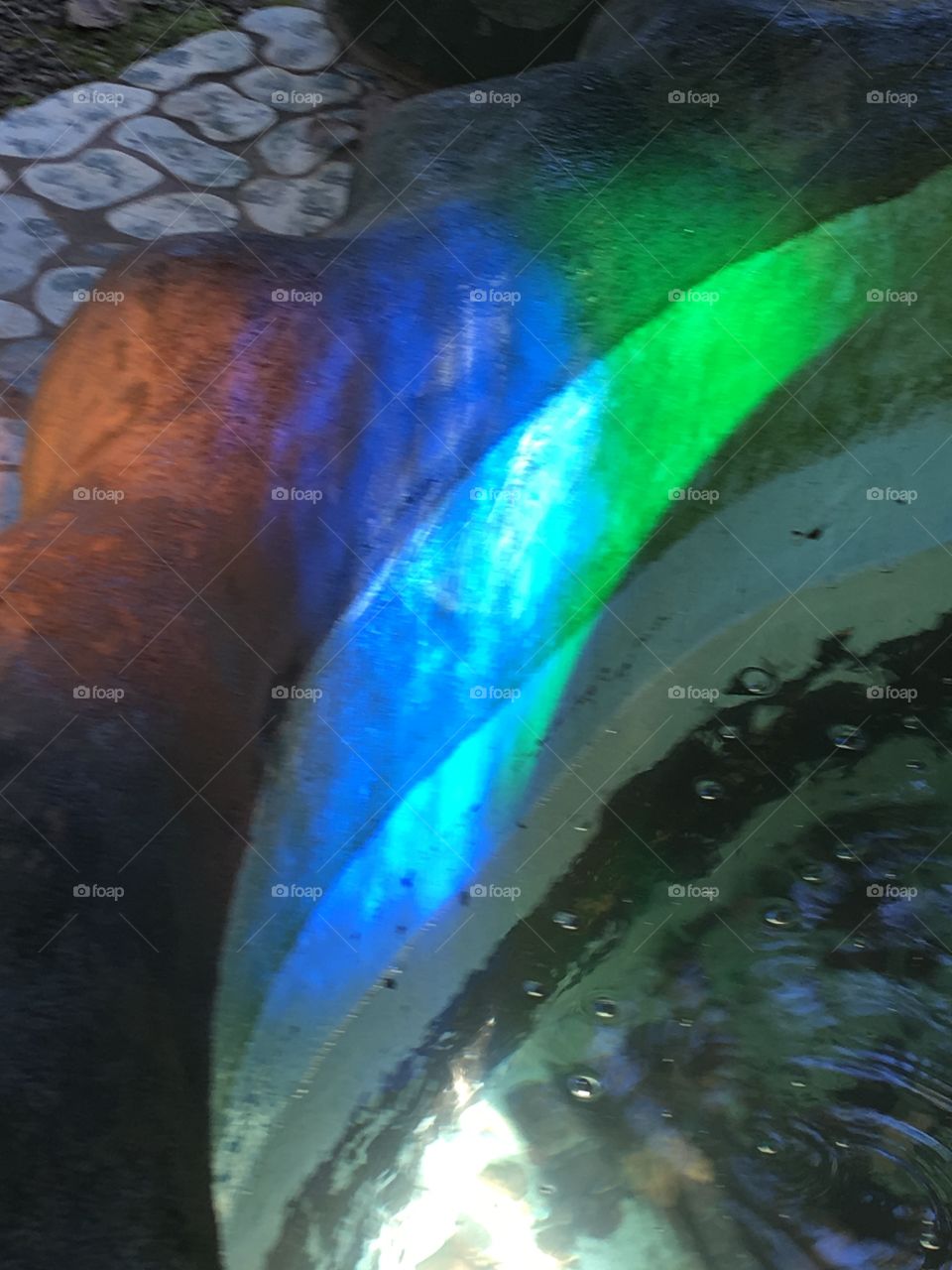 Colors bouncing off of a water fountain at the Terra studios. Blue and green rainbow.