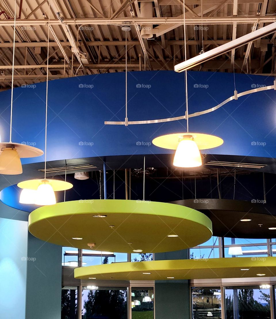 contemporary lighting fixtures against pop of bold blue and green colored structures in an Oregon marker cafe