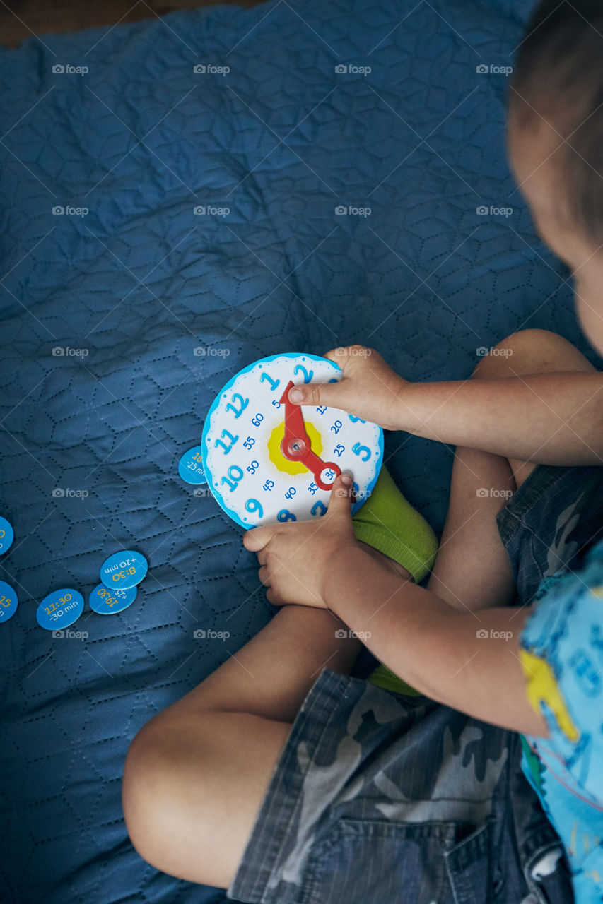 Kids learning how to tell time from clock and set the hands in the correct position. Teaching preschoolers tell time. Candid people, real moments, authentic situations