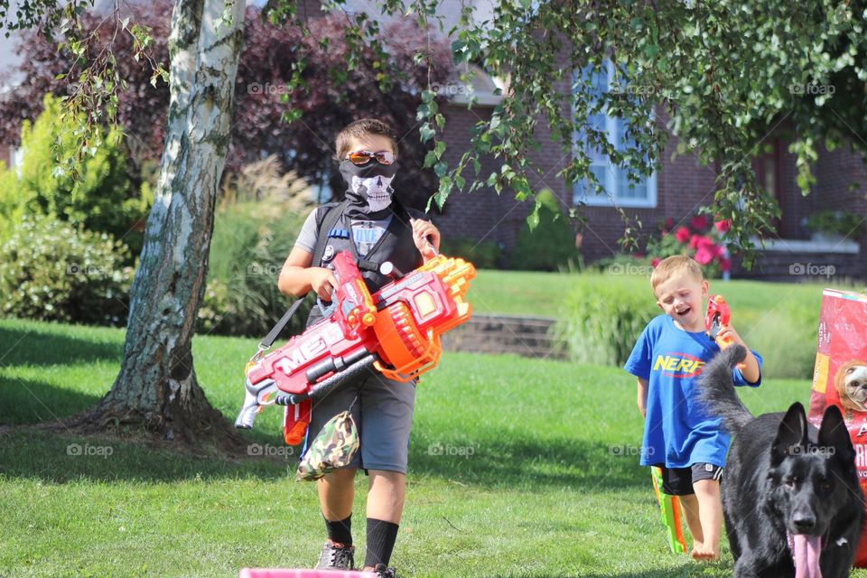 Children walking on grass holding water gun in hand