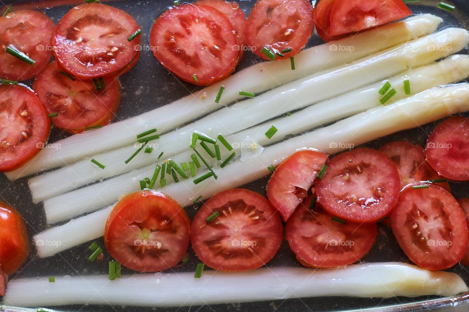 Asparagus and tomatoes with chives and marinade in a glass bowl