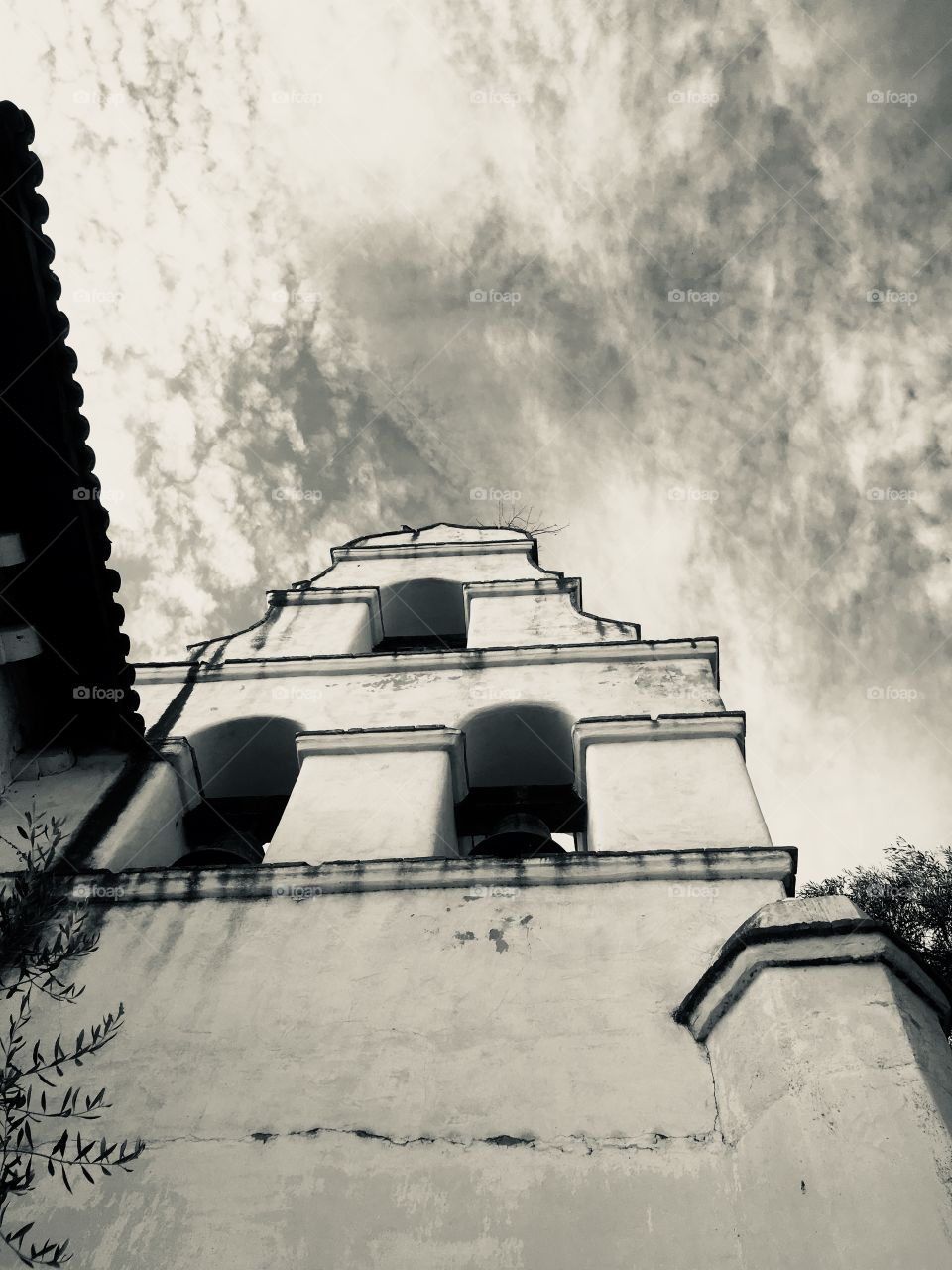 The impressive and haunting bell tower at Old Mission San Juan Batista reaches for the stark storm clouds above.
