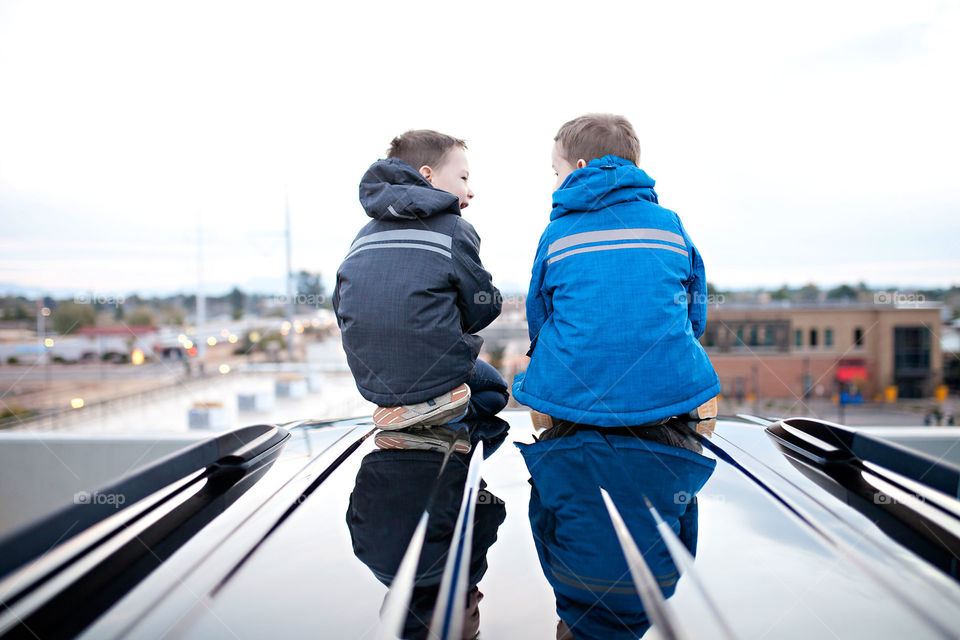 Boys sitting and talking on car watching sunrise 