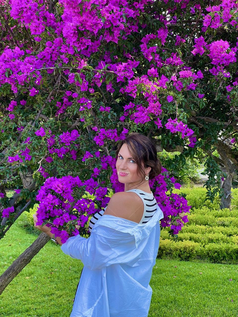 Beautiful girl in Greece in a white shirt near lilac bushes