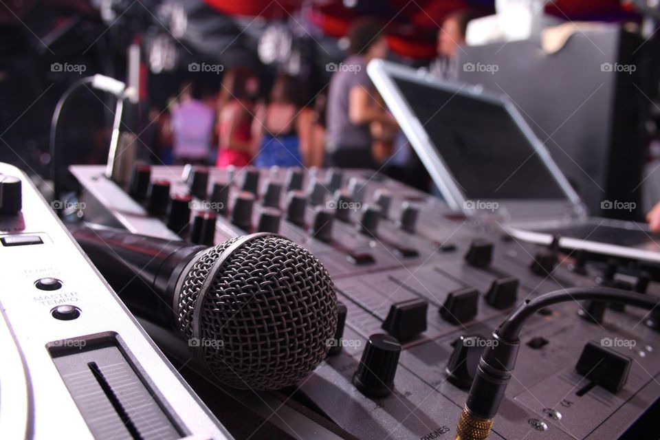 Dj station, mixing console, microphone and turntable. People dancing